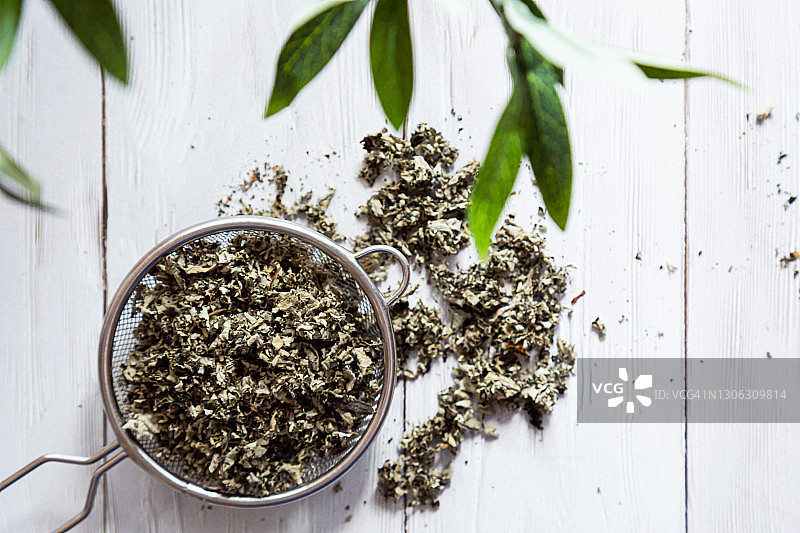 干覆盆子叶子在滤茶器特写。替代草药。健康的生活方式的概念。有机的，天然的草药茶放在一个轻木桌上。图片素材