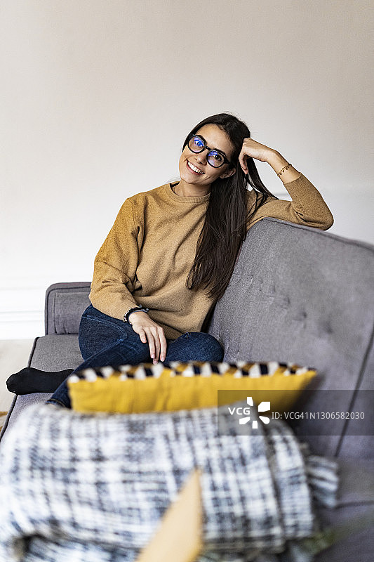 戴眼镜的女人坐在家里的沙发上微笑图片素材