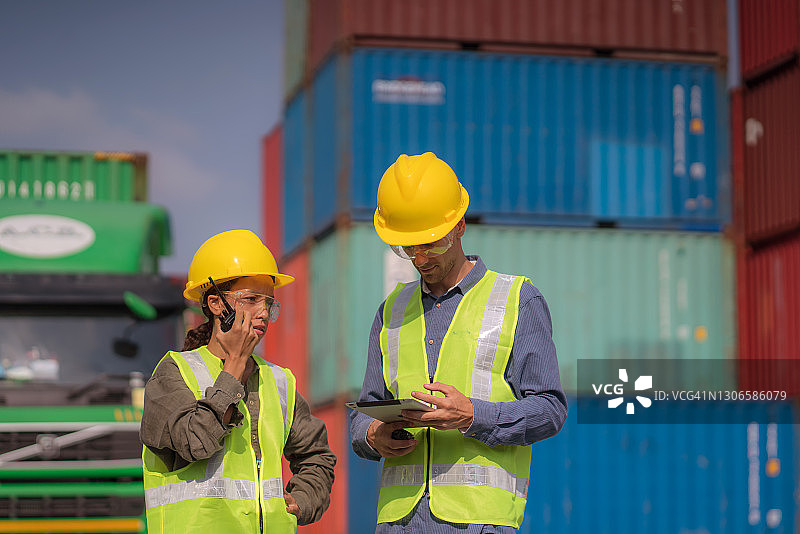 戴安全帽和穿安全背心的工人控制从货轮上装卸进出口集装箱。图片素材
