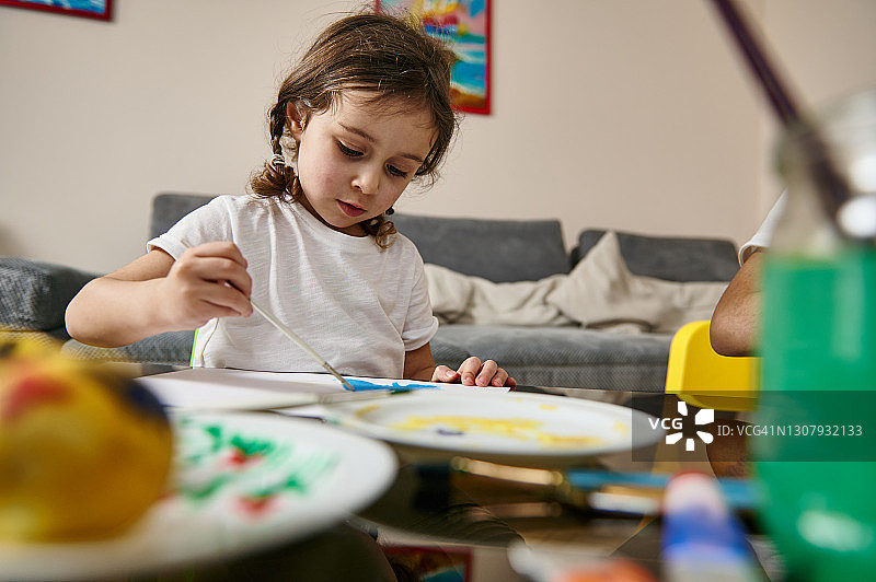 一个小女孩在家里用水彩颜料画肖像图片素材