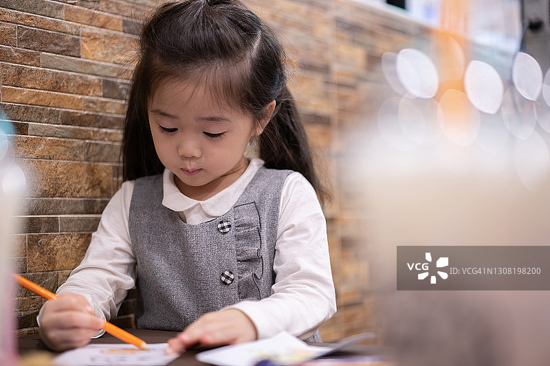 回到学校。快乐微笑的小学生在课桌上画画。可爱的学龄前儿童在家画画。小女孩用铅笔画画图片素材
