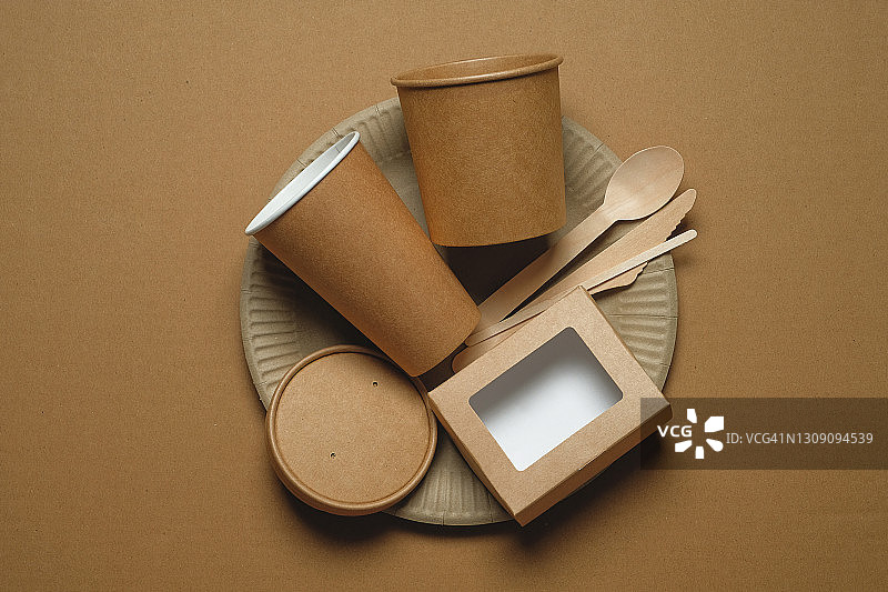 可降解的一次性餐具，由可回收的塑料和纸在米色背景。保护、关怀、环保的理念。图片素材