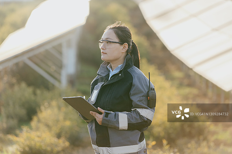 日落时分在太阳能发电站工作的亚洲女工程师图片素材