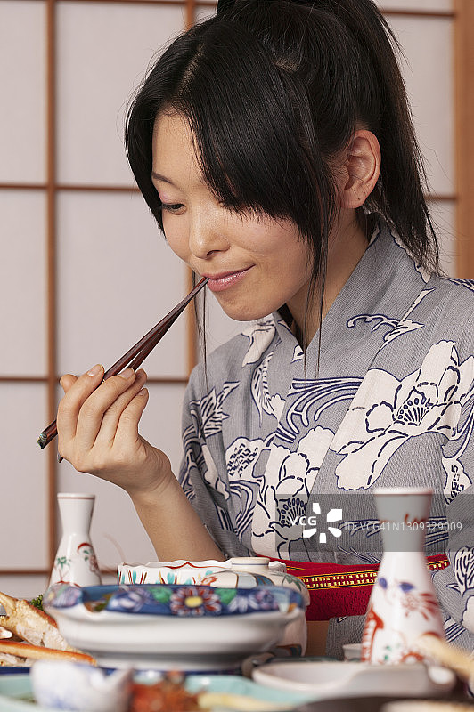 穿着和服的年轻女子用筷子吃传统的日本饭图片素材