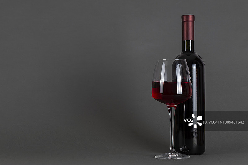 灰色背景上的红酒酒瓶和酒杯。酒饮文化概念。图片素材