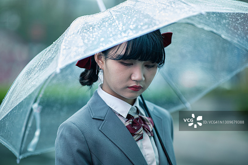 十几岁的女孩撑着伞站在雨中图片素材