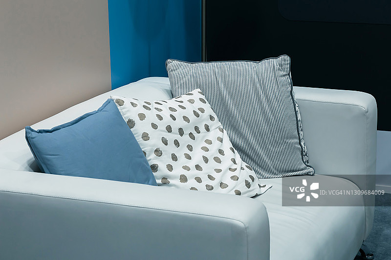 现代的室内设计，家庭舒适和装饰，白色沙发与枕头在客厅靠墙的地板上以蓝色调图片素材