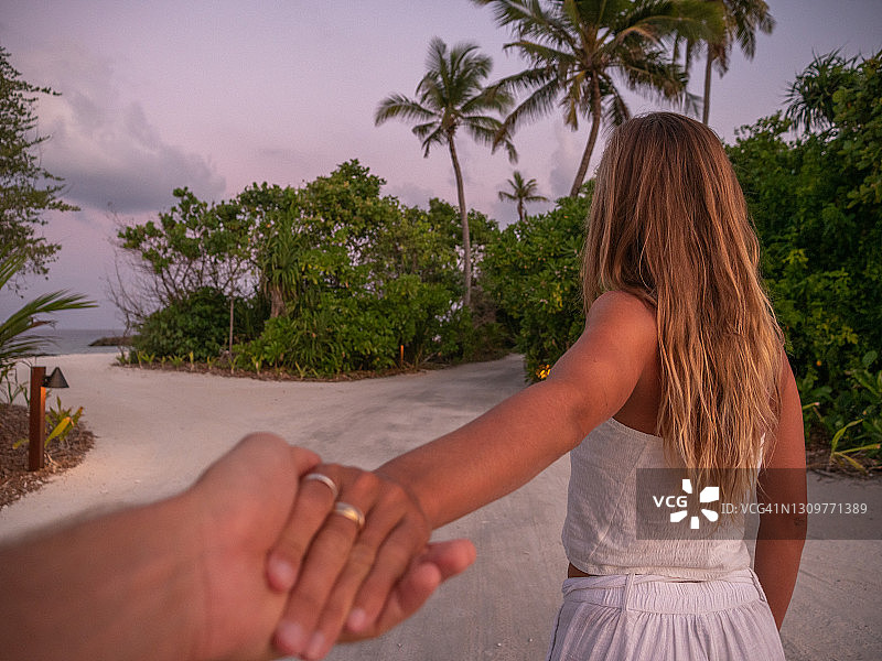 日落时分，一对夫妇在热带岛屿上牵着手图片素材
