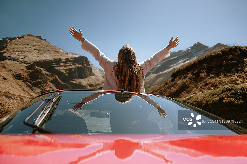 一名年轻女子从汽车天窗中举起双臂图片素材