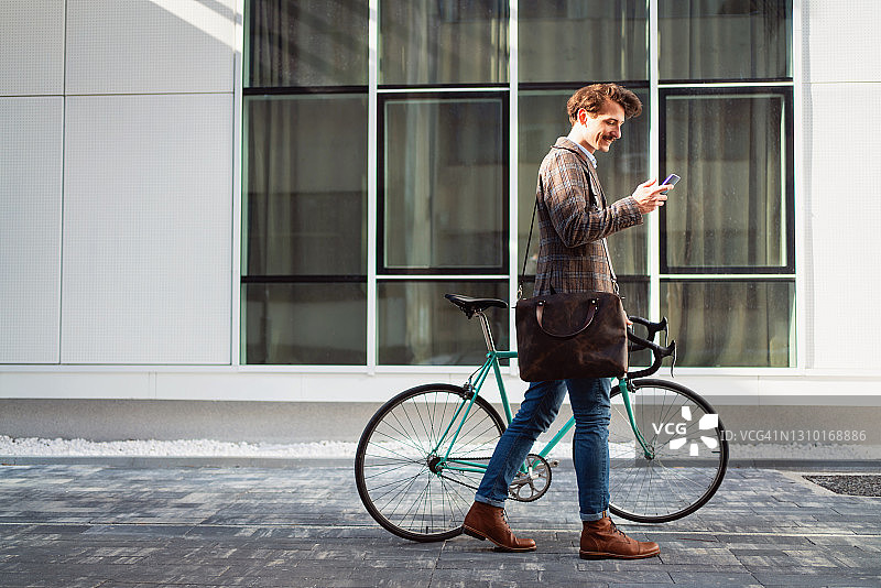 一个年轻的商人一边用智能手机一边骑自行车图片素材