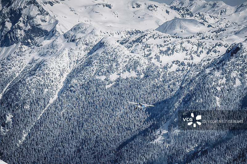 一架小型的布什飞机在冬天飞过引人注目的海岸山脉图片素材