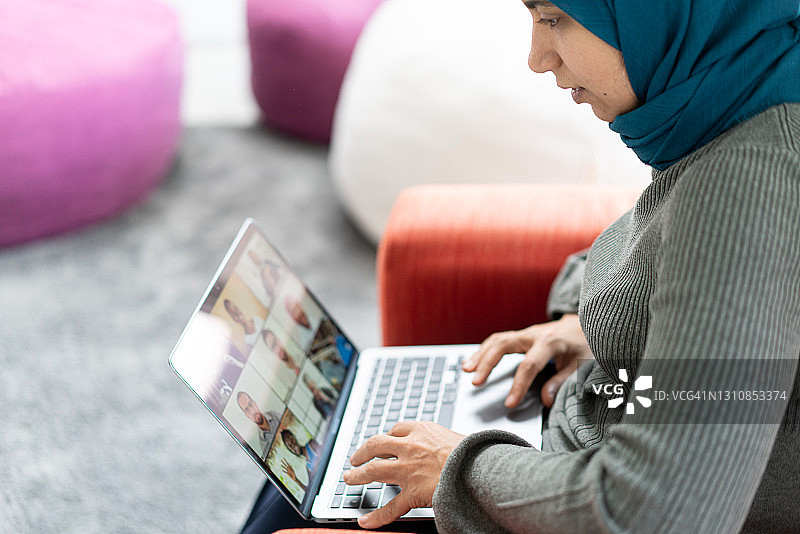 戴着头巾的女人用笔记本电脑与人在线交流图片素材