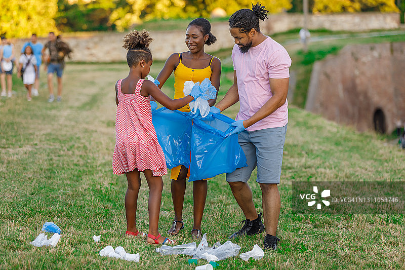 快乐的非裔美国家庭正在收集垃圾袋里的垃圾。图片素材