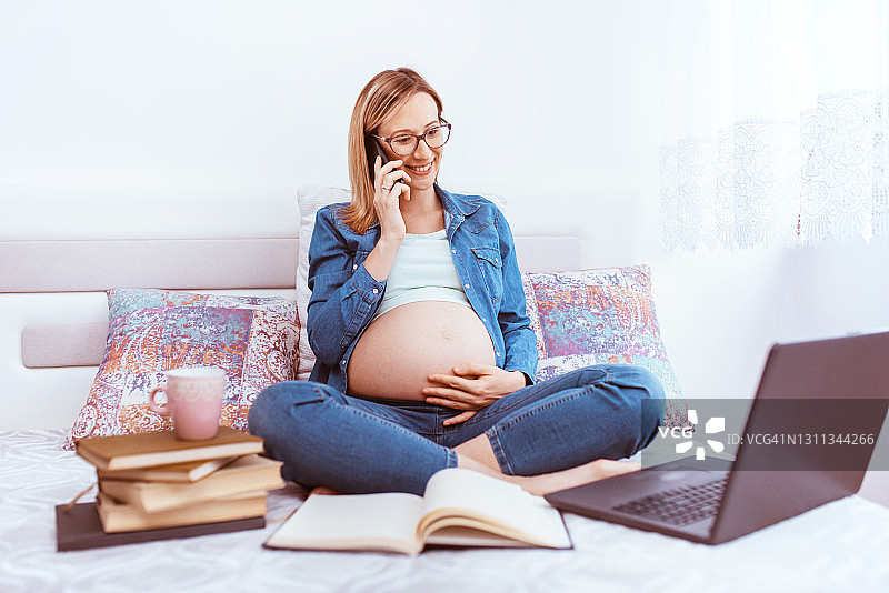 快乐的年轻孕妇用手提电脑工作图片素材