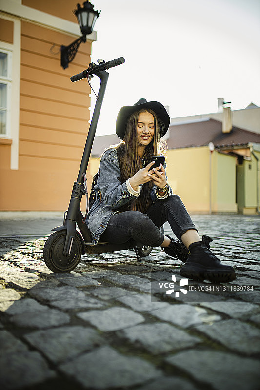 一名妇女坐在电动推车上，休息时正在用她的智能手机图片素材