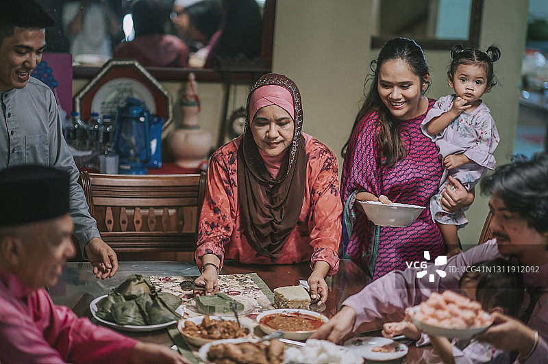 斋月开斋节马来人祖母，儿子和儿媳在餐厅为家人提供食物图片素材