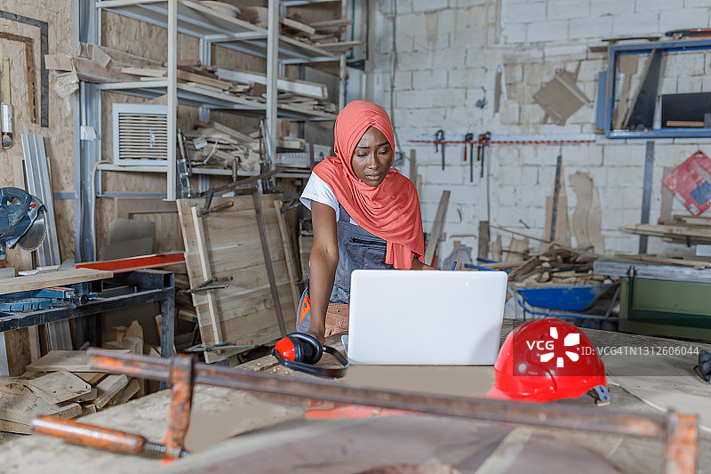 一个中东民族的年轻女子在木工车间工作。图片素材