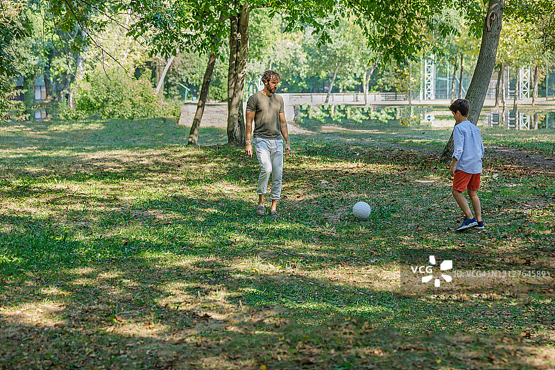 快乐的爸爸和儿子在户外玩足球。图片素材