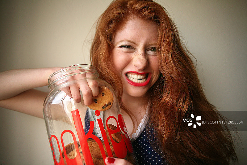吃糖癖:吃饼干罐里的饼干的红发女人，吃糖果的女人图片素材