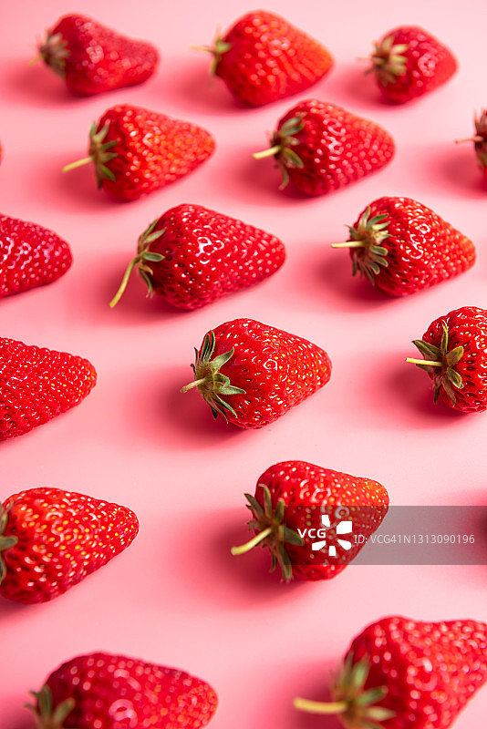 鲜嫩多汁的草莓在粉红色的背景上的特写图片素材