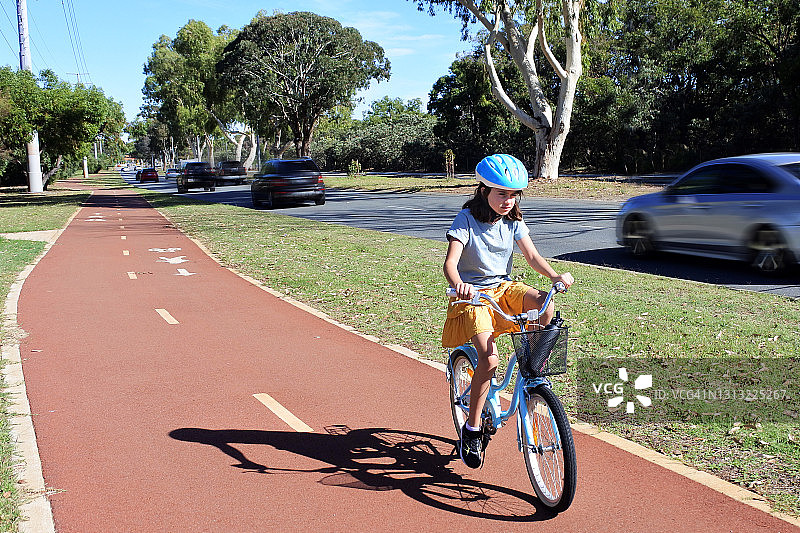 年轻女孩骑在一个城市的自行车道前视图图片素材