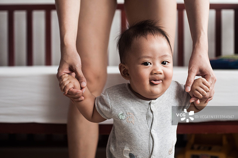 一名东南亚男婴和母亲在家里第一次走路图片素材