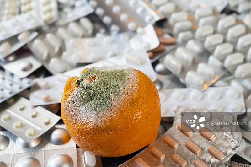 一种正在长绿霉的橘子在大量的药片上。图片素材