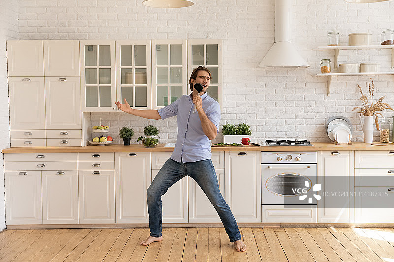 有趣的人对着厨房用具唱歌，跳舞，在厨房里玩图片素材