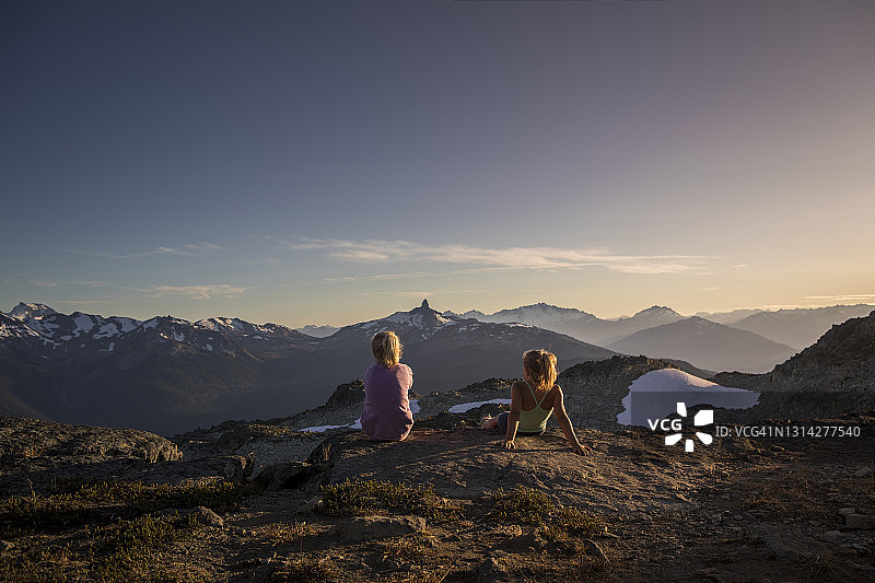 两个女孩在惠斯勒山顶欣赏日落。图片素材
