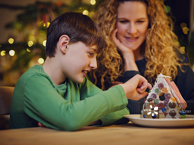 微笑可爱的男孩装饰姜饼屋的母亲在圣诞节图片素材