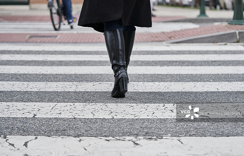 穿靴子走在街上的女人。图片素材
