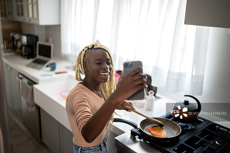 年轻女子在家做饭和视频通话图片素材