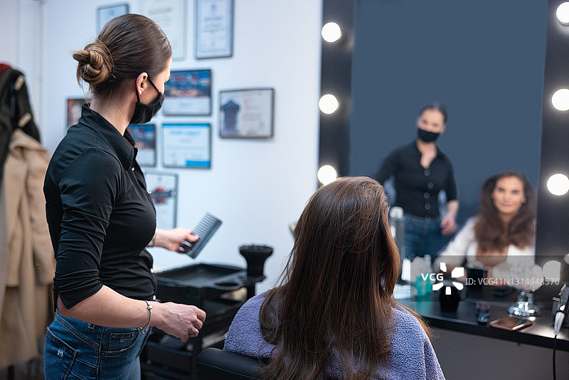 美发师拿着梳子在沙龙里和女顾客交谈图片素材