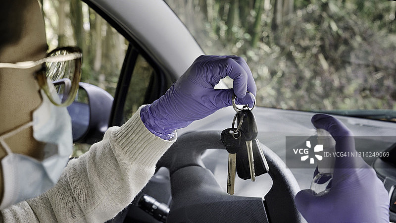 一名西班牙裔年轻女子在汽车钥匙上喷洒酒精以预防病毒图片素材