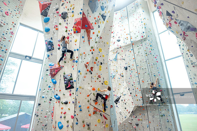年轻女性在健身房攀爬墙壁的低角度视角图片素材