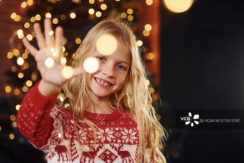 可爱的小女孩在圣诞树附近的室内庆祝新年图片素材
