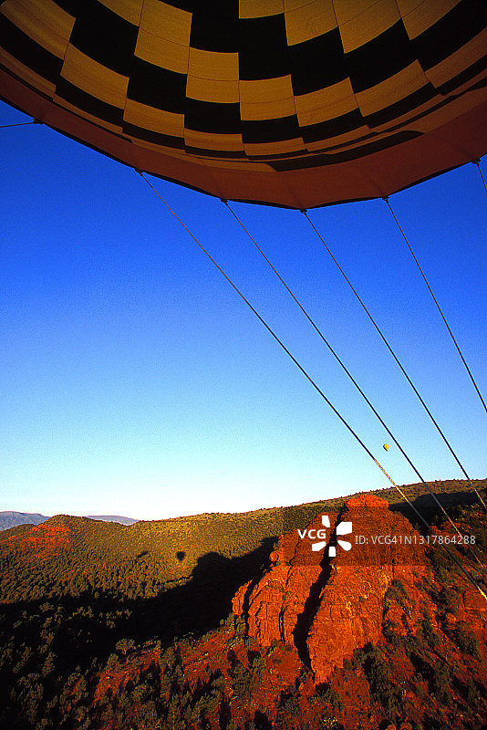 在亚利桑那州塞多纳上空，从充气的热气球包裹的篮子中拍摄，还有一个在远处有阴影的类似的气球图片素材