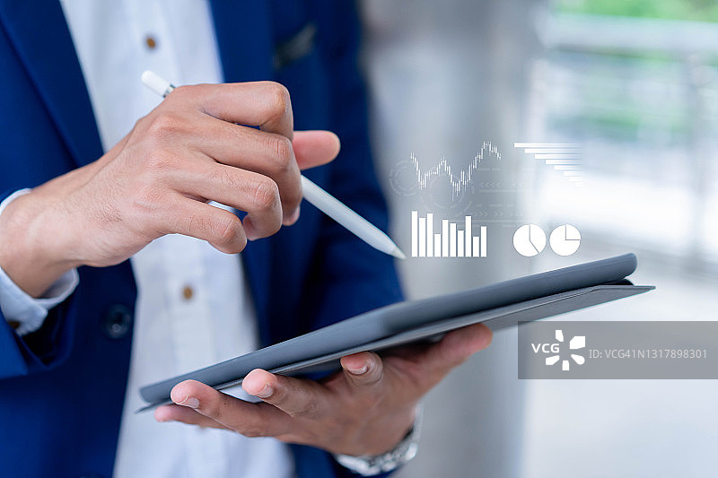 接近投资者的手用触控笔指向虚拟统计图表屏幕显示公司利润报告每月在会议活动在未来的商业战略概念图片素材
