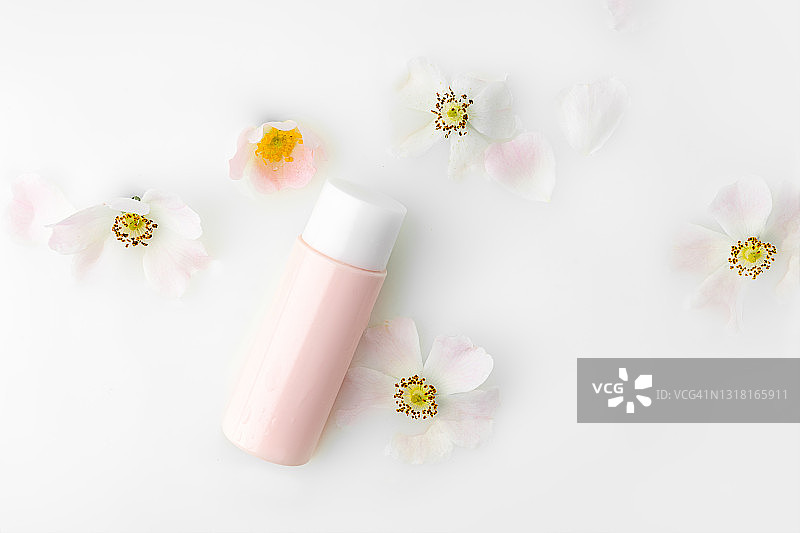 美丽的白色玫瑰花和清洁牛奶在一个粉红色的小瓶牛奶浴。图片素材