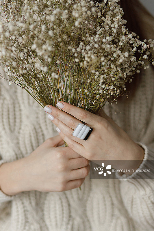 美丽时尚的女人用现代的方形戒指拿着干花，特写。美容和护理图片素材