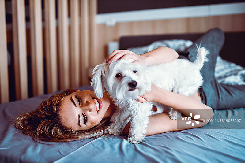 在床上和宠物狗玩耍的女人图片素材