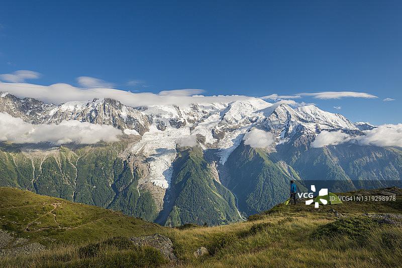 一名男子在GR5步道或Grand Traverse des Alps附近的避难所德贝拉查特(Refuge De Bellachat)与远处的勃朗峰(Mont Blanc Massif)景色图片素材