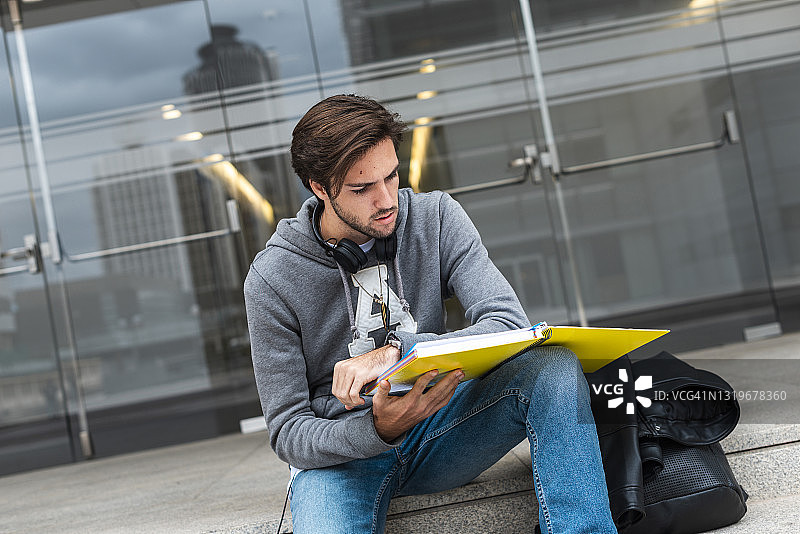 一个年轻人坐在校园的台阶上看笔记本图片素材