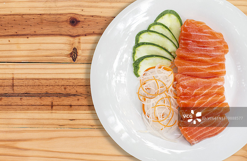 生鲑鱼，红色的鱼和蔬菜在白色的盘子与木制的背景图片素材