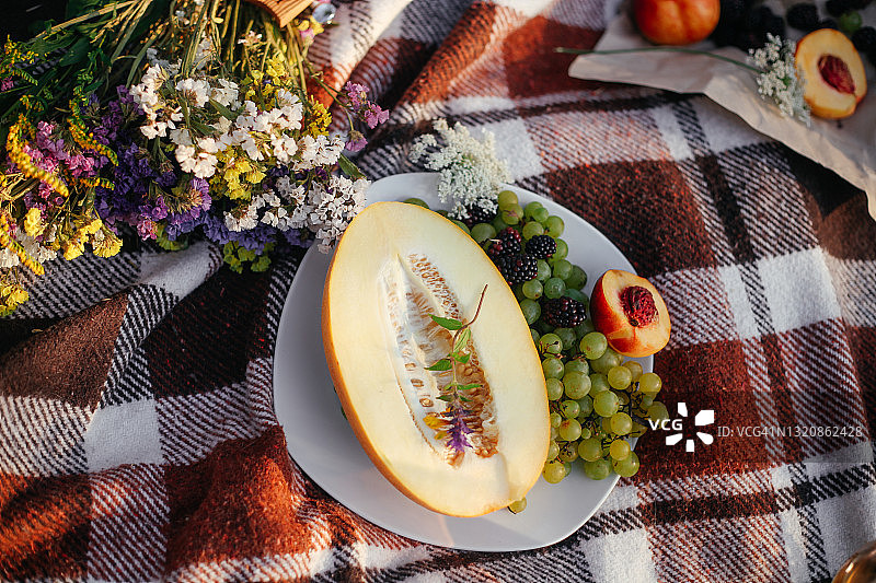 夏季野餐。瓜果、葡萄、桃果盖上花。图片素材