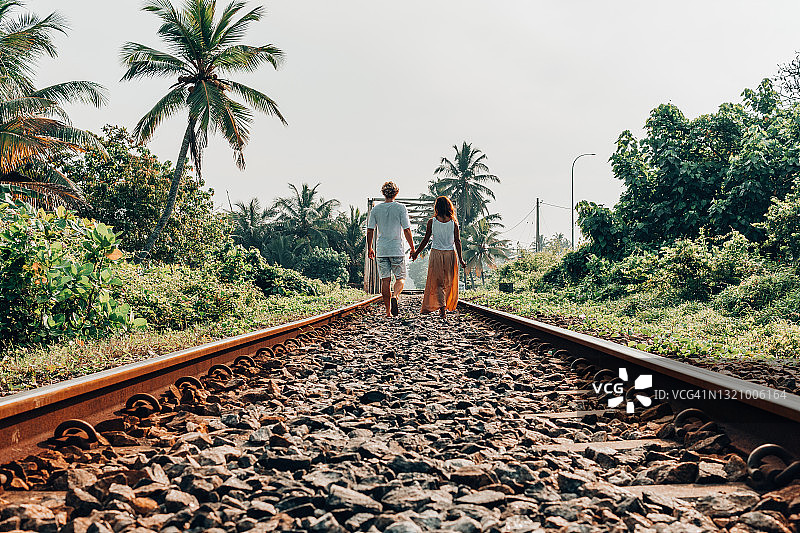 一对情侣在斯里兰卡风景优美的铁路上手拉手浪漫散步图片素材