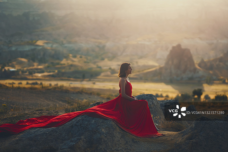 穿着红衣服坐在岩石上的年轻女子图片素材