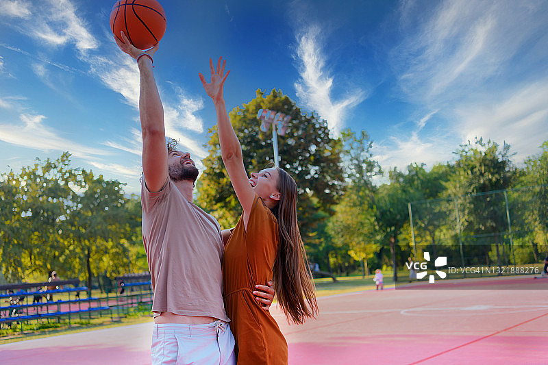 一对快乐的小情侣在户外玩篮球。图片素材