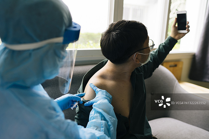 亚洲患者在疫苗接种中心与医生自拍合影，心情轻松舒适图片素材