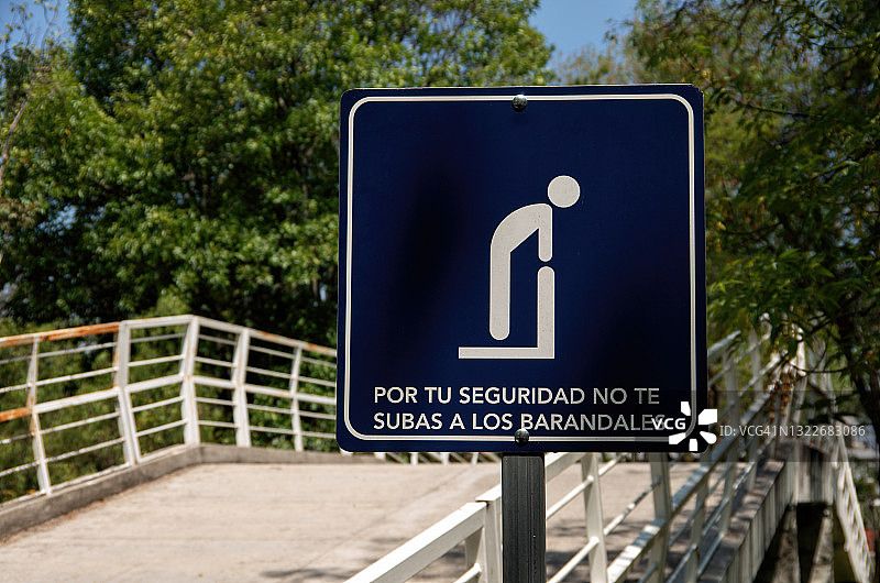一个用西班牙语写着“Por tu seguridad no te subas a los barandales”的标牌(为了您的安全，请勿爬上桥的栏杆)图片素材